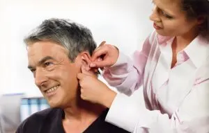 The audiologist is fitting a hearing aid